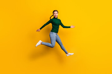 Fototapeta na wymiar Full length body size photo smiling woman jumping high laughing wearing jeans isolated on vivid yellow color background