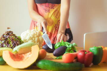 Woman cutting different vegetables. Mother preparing vegetarian food for her children. Healthy food and vegan style concept.