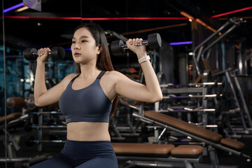Fototapeta na wymiar young Athletic woman with muscular body exercising Crossfit. Asian Woman in sportswear doing a workout with the dumbbell at the gym