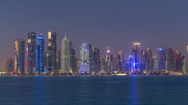 Doha downtown skyline day to night transition timelapse, Qatar, Middle East. Illuminated skyscrapers on a West Bay reflected in a water of Gulf