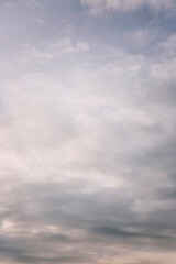 Obraz premium Beautiful blue dramatic sky with clouds at sunrise. Background. Space for text. Vertical.
