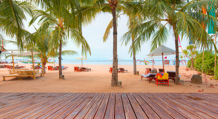 People sunbathing under palm tree on hot and sunny day on beach - Bali, Indonesia 
