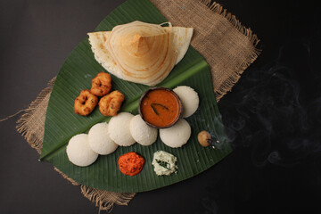 Group of South Indian food like Masala Dosa, Idli, Wada or vada, sambar, served over banana leaf...