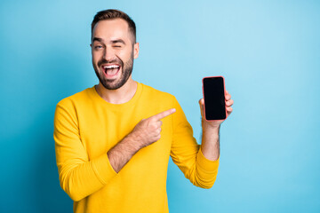 Photo portrait of man pointing finger display of smartphone copyspace winking isolated on vibrant...