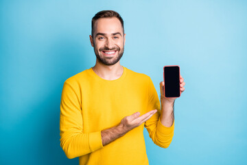 Photo portrait of man showing screen smartphone empty space smiling isolated on bright blue color...