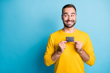 Photo portrait of student cunning showing credit card looking empty space isolated on vivid blue...