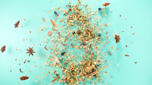 Spices, orange zest and star anise in bottle stencil shape exploding and flying up on blue background