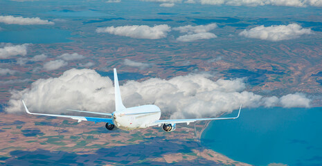 Fototapeta premium White passenger airplane over the clouds - Travel by air transport