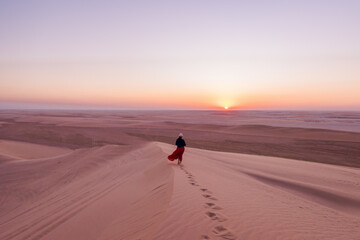 Woman on a hill in the desert at sunset, Qatar