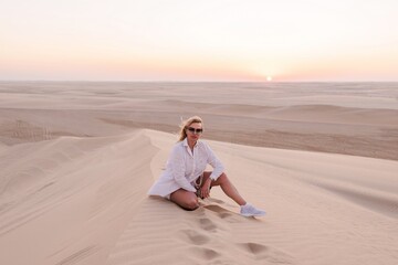 Fototapeta na wymiar Woman on a hill in the desert at sunset, Qatar