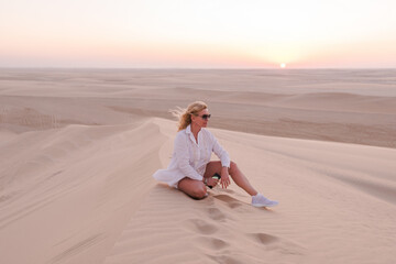 Fototapeta na wymiar Woman on a hill in the desert at sunset, Qatar