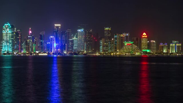 Doha skyscrapers in downtown skyline night timelapse, Qatar, Middle East Illuminated towers on a West Bay reflected in a water of Gulf.