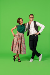 Disco. Old-school fashioned young woman dancing isolated on green studio background. Artist fashion, motion and action concept, youth culture, fashion returning. Young stylish man and woman.