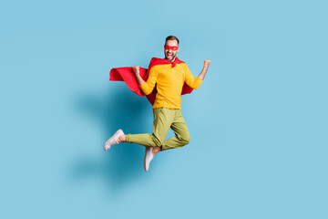 Full length body size photo of hero in mantle mask jumping high gesturing like winner isolated on vivid blue color background