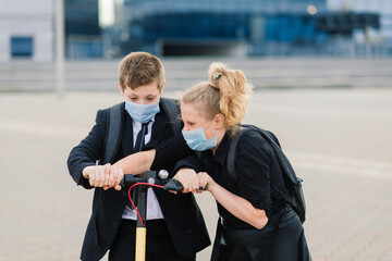 Happy school children with backpacks and scooters outdoors in protective mask