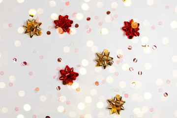 Many gift bow red and gold colors on white background. Decoration festive golden glitter on grey background. Minimal creative winter layout