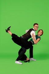 Fun. Old-school fashioned young woman dancing isolated on green studio background. Artist fashion, motion and action concept, youth culture, fashion returning. Young stylish man and woman.