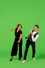 Step. Old-school fashioned young woman dancing isolated on green studio background. Artist fashion, motion and action concept, youth culture, fashion returning. Young stylish man and woman.