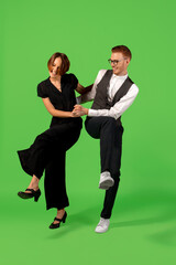 Rock n roll. Old-school fashioned young woman dancing isolated on green studio background. Artist fashion, motion and action concept, youth culture, fashion returning. Young stylish man and woman.