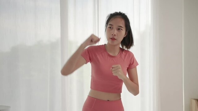 footage shot of beautiful Asian woman doing exercise Round boxing in the room.
