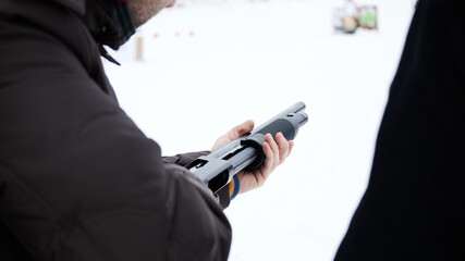 The shooter inspects his gun in a jacket in the winter