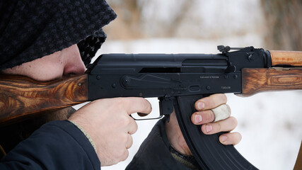 Eastern soldier take aim with a machine gun on a background of snow. Bandaged finger. 7.62 automatic