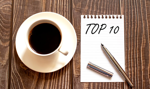 TOP 10 - white paper with pen and coffee on wooden background