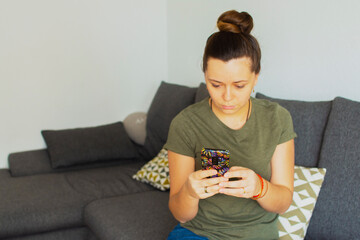 Girl sitting on the couch and writing a message on the phone