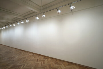 Interior of a empty white wall in perspective with spot lights at art gallery