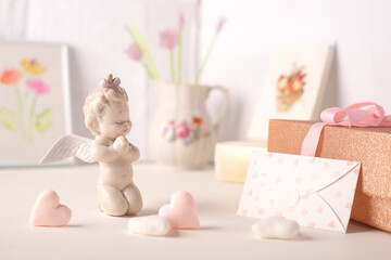 Fototapeta na wymiar ceramic cupid figurine letter with hearts and gift