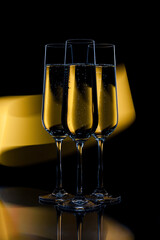 Elegant champagne flutes on black background with yellow light trace.