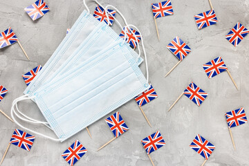 White medical mouth masks and United Kingdom flags on gray background. Coronavirus Covid-19...