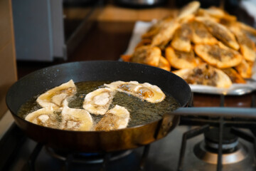 Gyoza dumplings with mushroom filling frying in hot pan. Golden crunchy dumplings cooking in oil.