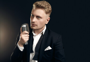 Naklejka premium Handsome singer in elegant tuxedo and bow tie with vintage microphone