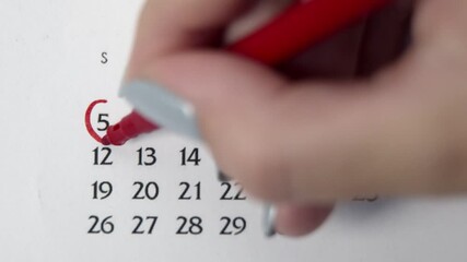 Female hand circle day in calendar date with a red marker. Business Basics Wall Calendar Planner and Organizer. APRIL 5th