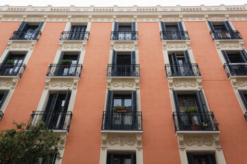 Brown building front facade with small balconies in downtown Madrid street. Residential neighborhood, real estate business, low angle perspective concepts