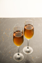 Blurred background. Two glasses of champagne on the black table. Alcoholic drink: champagne, beer, white wine. New year and Christmas background. Valentine's Day. Vertical photo
