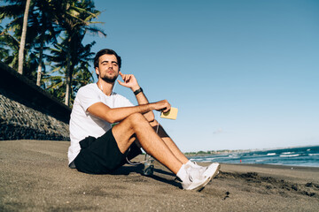 Man listening to music in earphones on shore