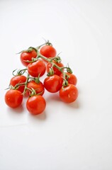 Bunch of fresh, red tomatoes with green stems isolated on white background.