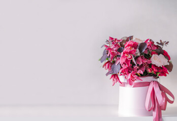 Orchids and roses in a round box on a light background stock photo. Bouquet of orchids and roses