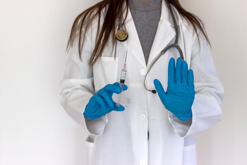 Young female doctor in blue gloves and a respirator mask for protection holds a vaccine for injection and gesture STOP sign. Stop virus. Syringe in doctor hand and sign stop. Health and people concept