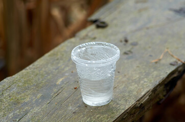 Plastic glass with water on wooden plank