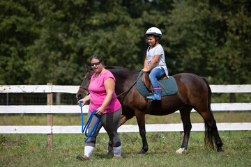 child riding a horse with instructor