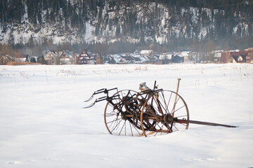 Porzucone narzędzie rolne na zaśnieżonym polu © michalsen