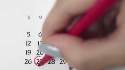 Female hand circle day in calendar date with a red marker. Business Basics Wall Calendar Planner and Organizer. APRIL 27th