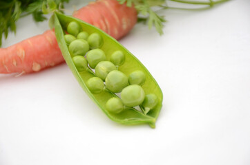 the green ripe peas with red carrot isolated on white background.