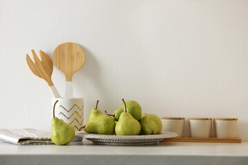 Plate with fresh ripe pears on white table