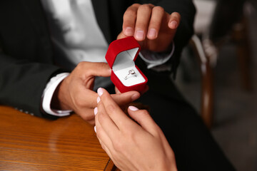Man with engagement ring making proposal to his girlfriend at table, closeup
