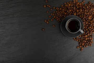 Hot coffee cup and coffee beans on black background top view
