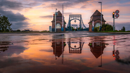 Die Kaiser-Wilhelm-Brücke in Wilhelmshaven mit Spiegelung in einer Regenpfütze. - obrazy, fototapety, plakaty
